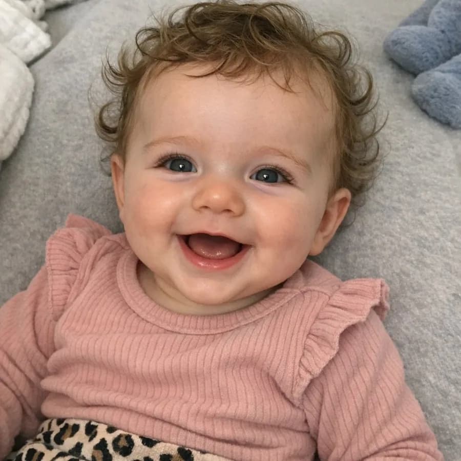 Baby photo of Milou with curly hair and pink clothing